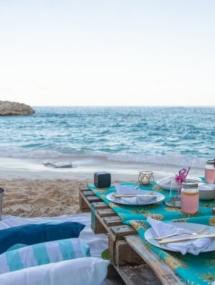 A luxe picnic table set up on the beach at dusk.