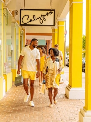 A couple are walking in hamilton by a bright yellow building.