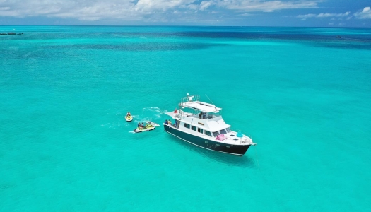 A boat on turquoise water near people on sea-doos 