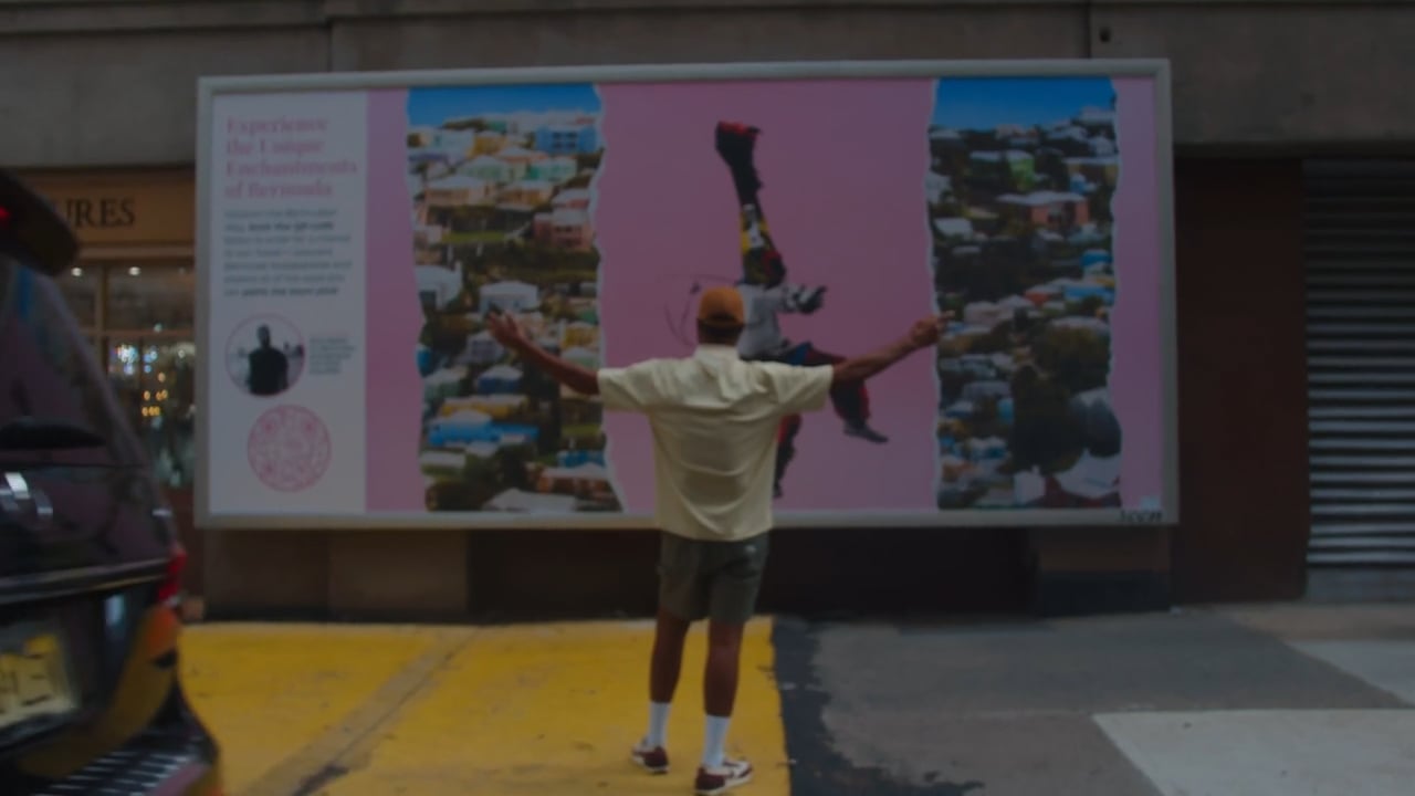 A man is posing in front of a billboard.