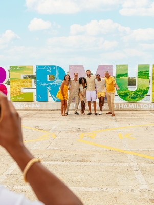 People posing by the Bermuda sign.