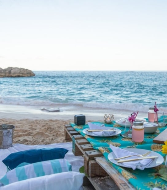 A luxe picnic table set up on the beach at dusk.
