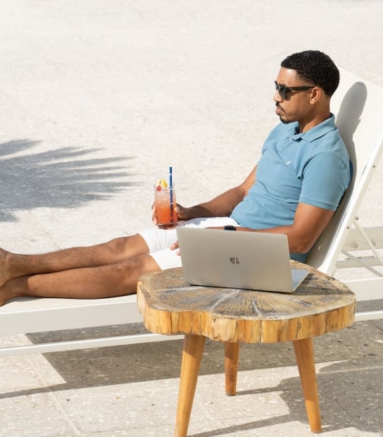 A man is sitting on a lounge chair by a lounge chat.