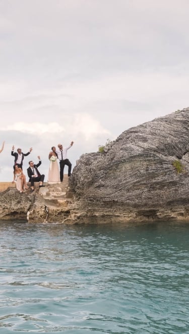 Couple jumping into water with people watching