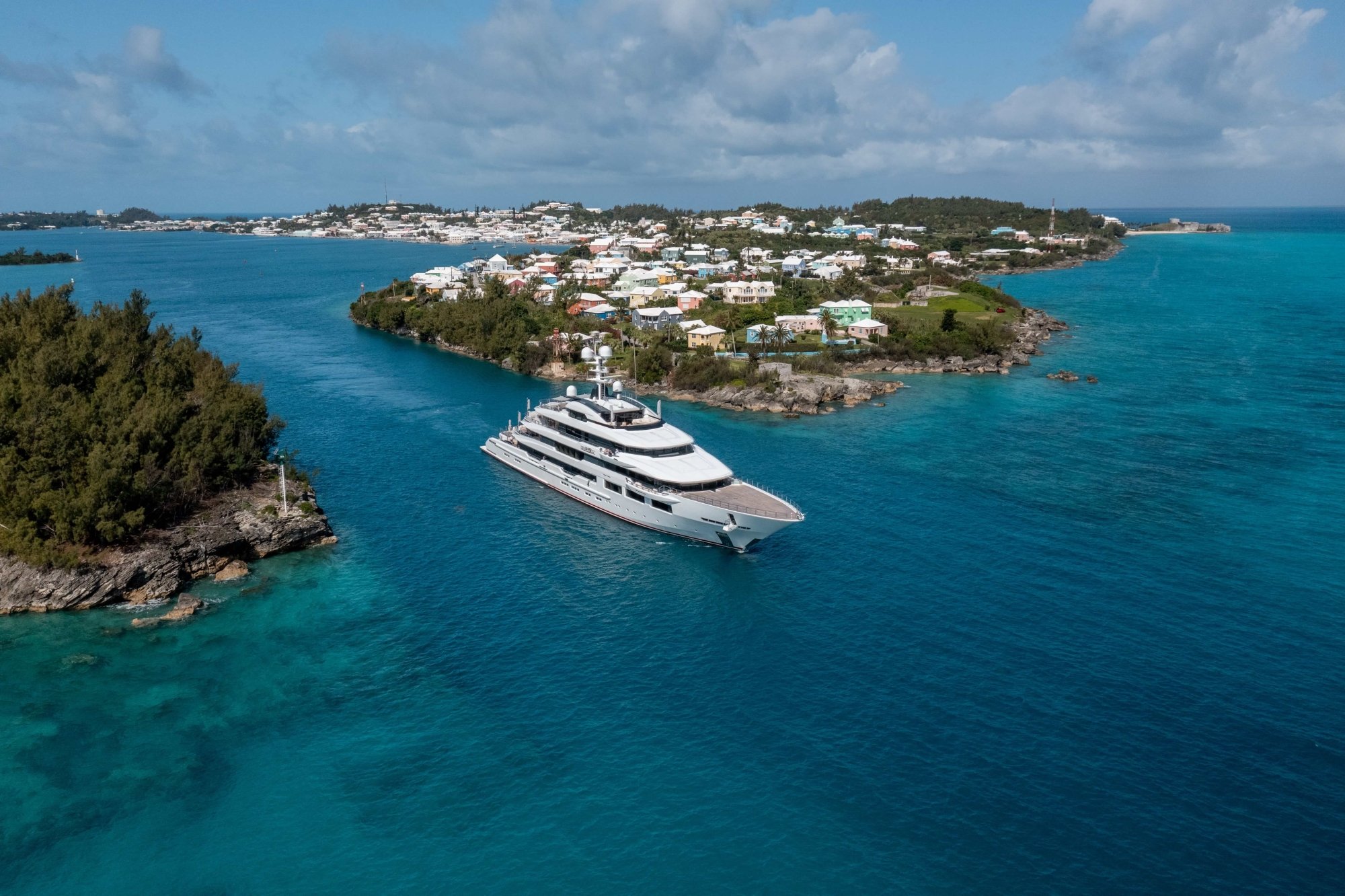 A large super yacht is exiting the channel on calm blue waters. 